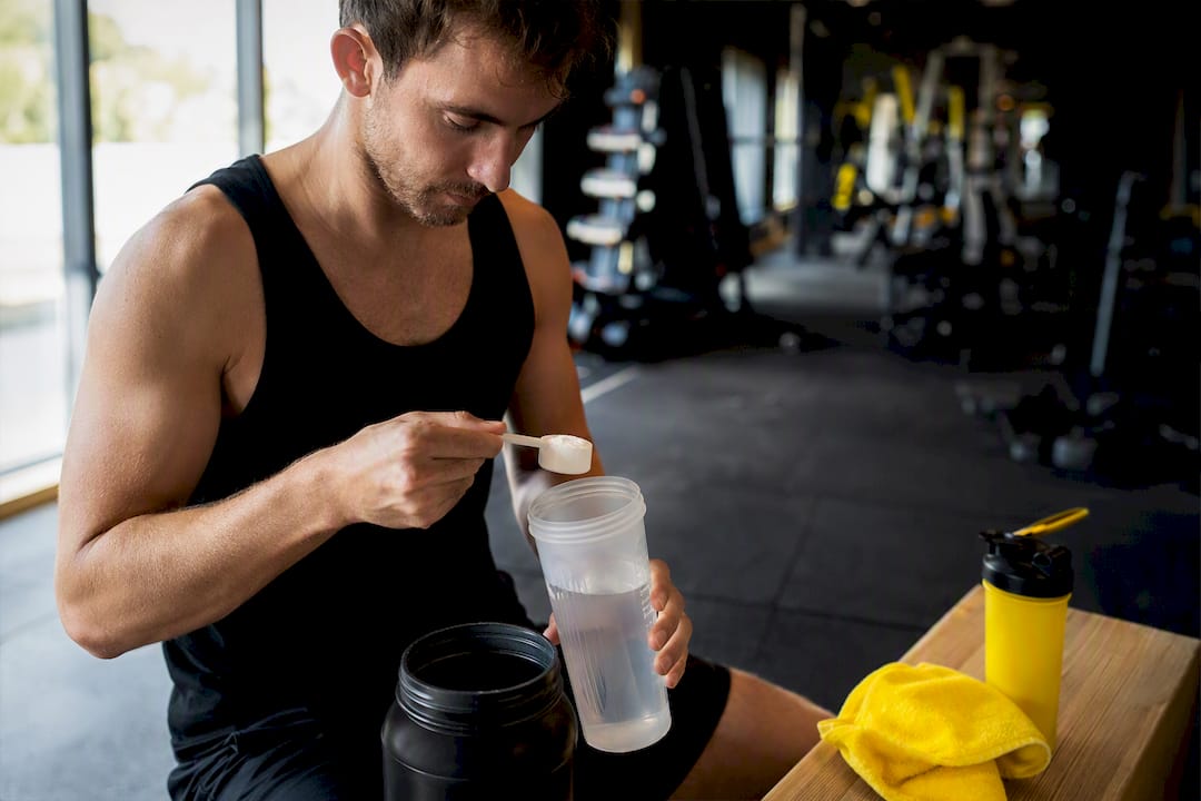 Sportif mesurant de la poudre de créatine à la salle de sport