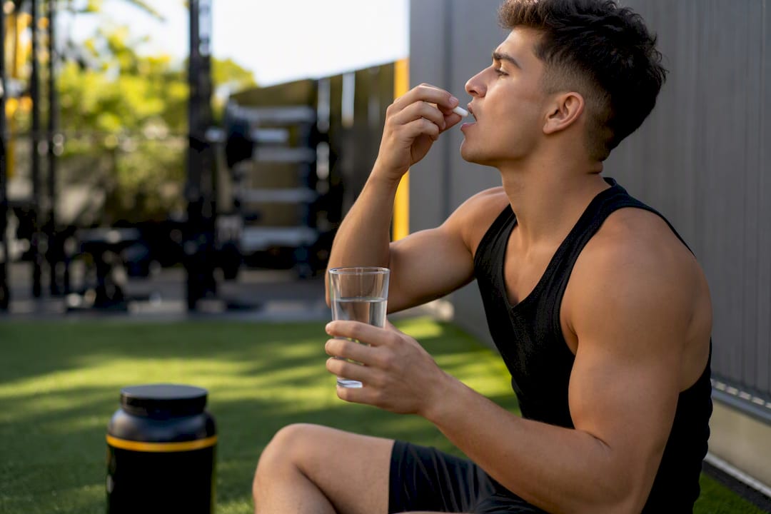 Athlète avalant une capsule probiotique avec de l'eau