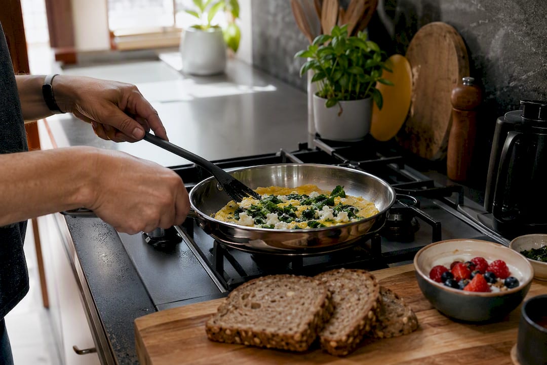 Mains en train de cuisiner une omelette protéinée aux épinards