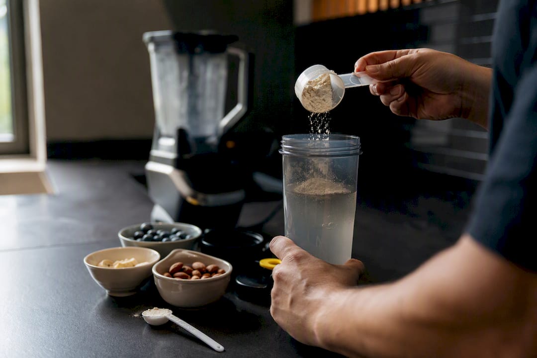 Mains mélangeant un shake protéiné dans la cuisine