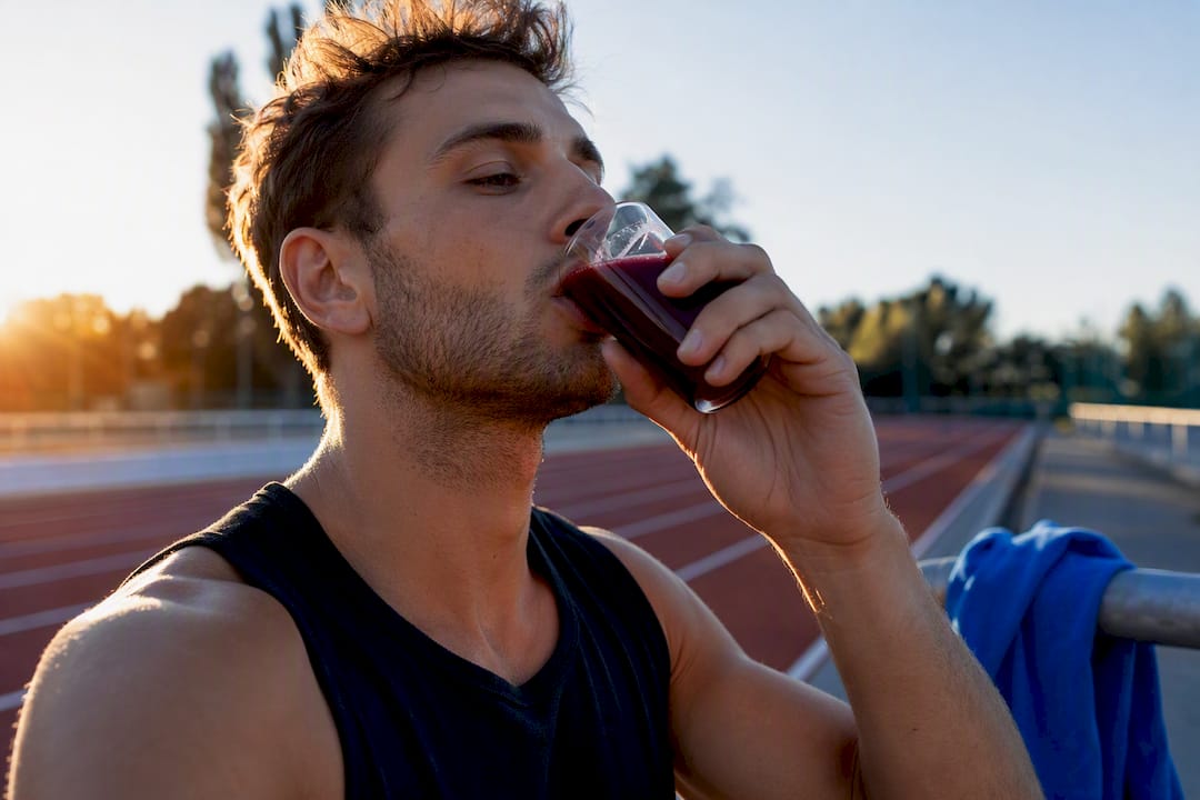 Un sportif amateur qui boit un shot de jus de betterave