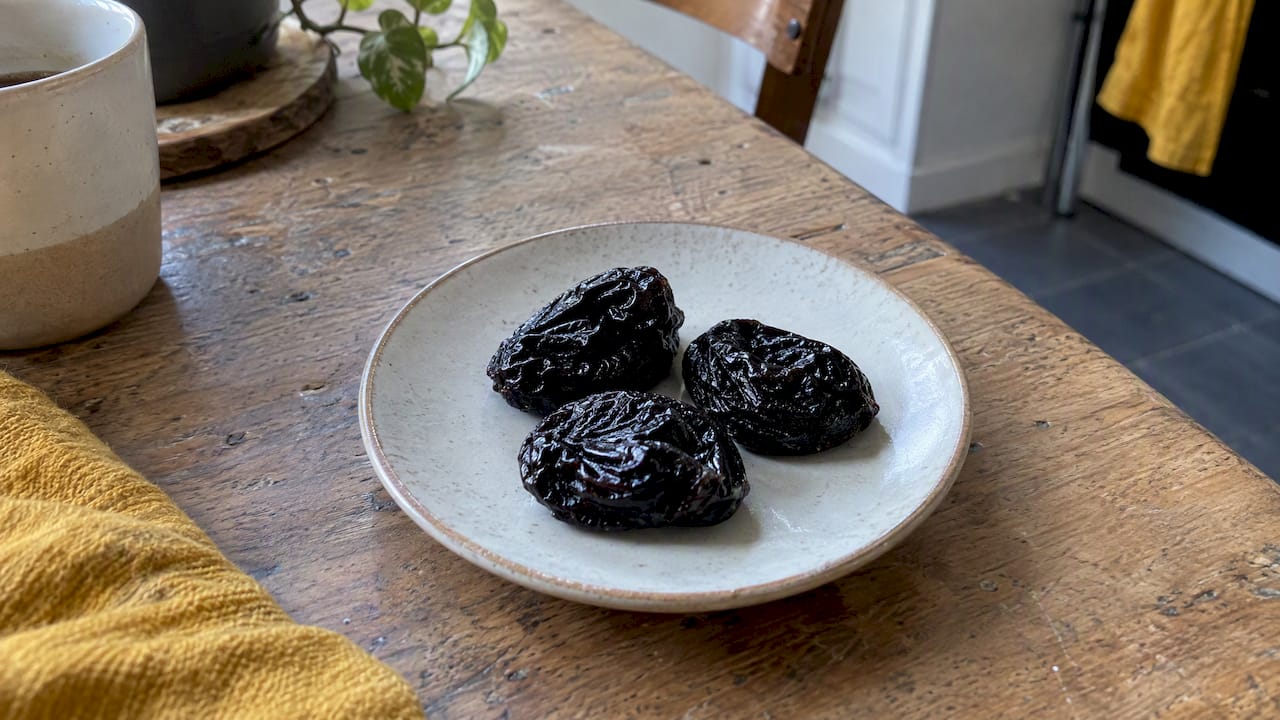 Trois pruneaux posés sur une assiette de collation